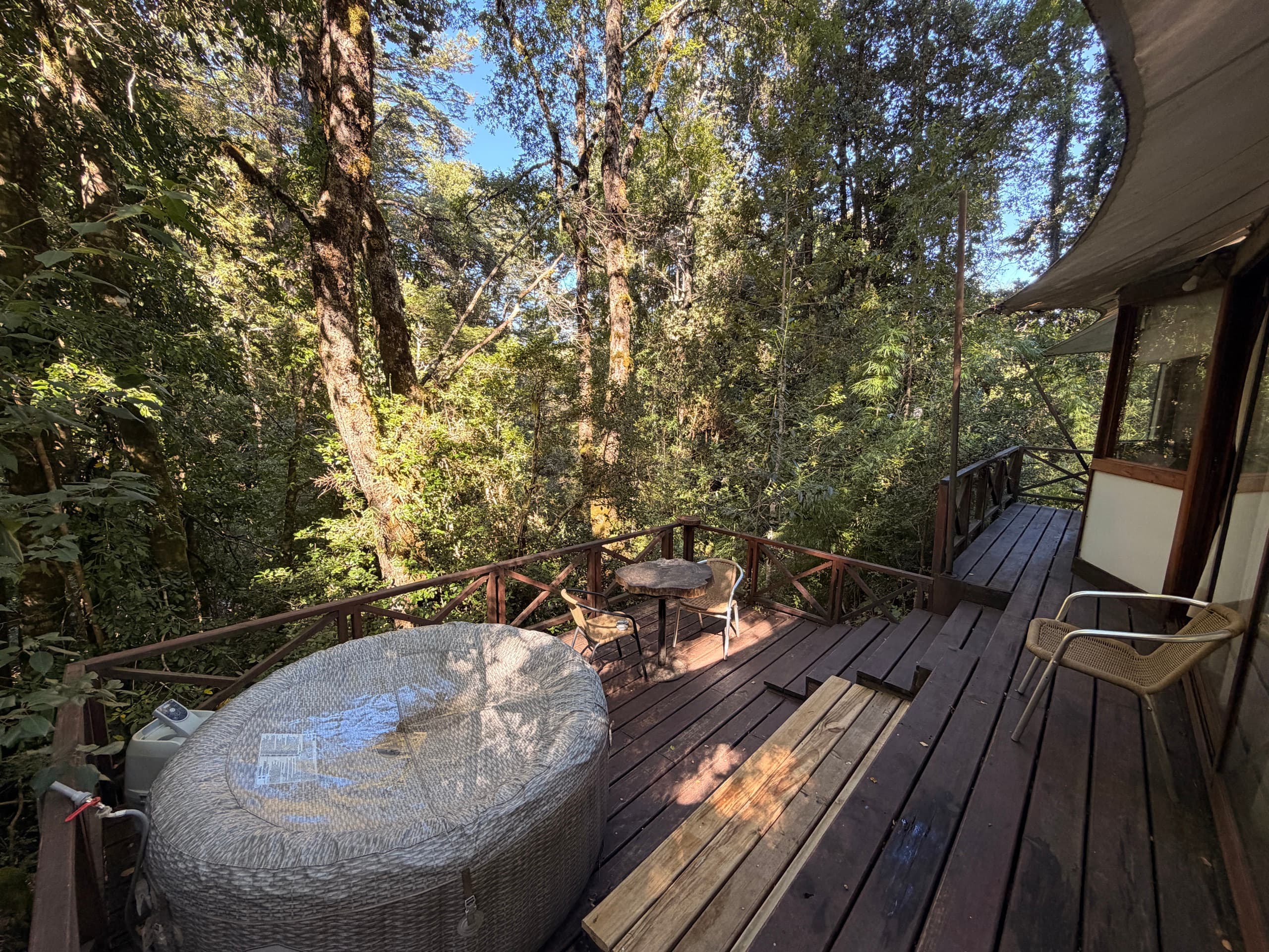 Cabaña con tinaja privada en el deck, inmersa en el bosque nativo
